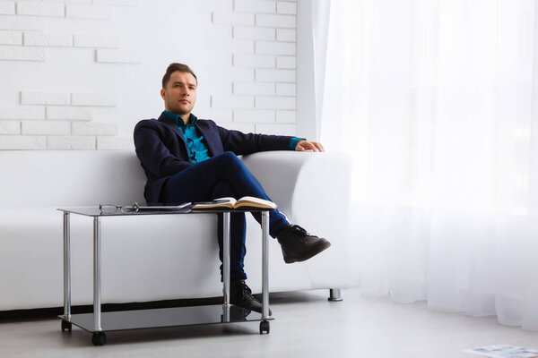 молодой бизнесмен на белом диване на белом фоне