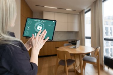 Akıllı ev sistemini kullanan ya da evden çıkmadan önce modern alarm sistemini çalıştıran hoş bir kadın. Mutlu kadın eve ya da daireye döndüğünde kolay güvenlik teknolojisini kapatıyor..