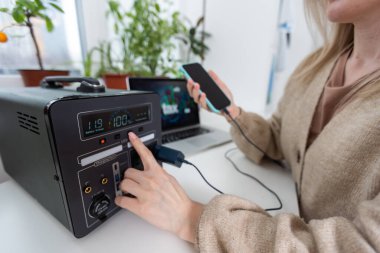 Cep telefonuna kablosuz ağda şarj oluyor ve tahta arka planda dizüstü bilgisayar kullanıyor..