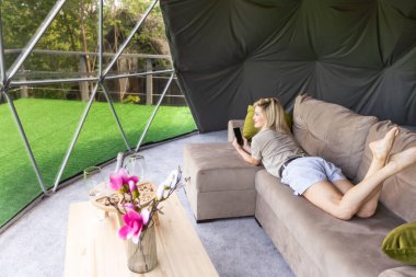 Evde dinlenirken akıllı telefon kullanan güzel bir kadının fotoğrafı..