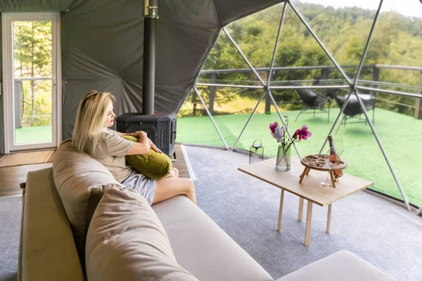 透明的泡沫帐篷在釉面 茂密的森林周围和内部 躺在窗台上的女人 — 图库照片