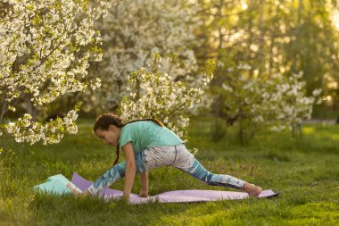 Güzel kız yoga egzersizleri yapıyor, küçük kız bahçede yoga egzersizleri yapıyor.