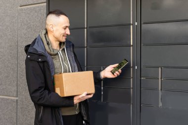 Depo Birimleri Bölümü. İnternette kiralık depolama üniteleri. Akıllı telefonu olan adam depoyu seçer. Web sitesinde depo kiralama. Kutuların yanında bir iş adamı. Arkaplanda bulanık depolama şirketi.