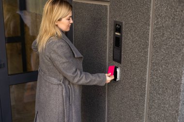 Bina girişinde dahili telefon kullanan kadın