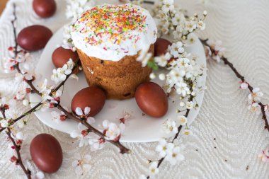 Paskalya pastası ve boyalı yumurta. Çiçek açan buket masanın yanında yatıyor.
