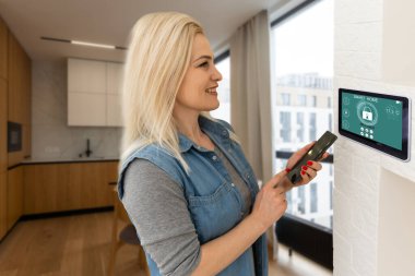 Oturma odasındaki duvara dijital dokunmatik ekran panelle evi kontrol etmek. Evdeki akıllı aygıtları yönetmek için akıllı ev ve mobil uygulama kavramı
