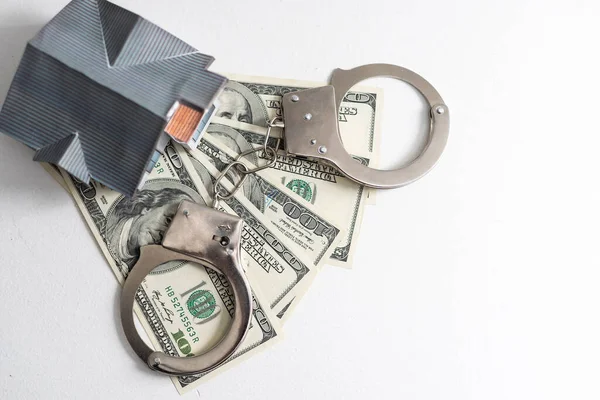iron handcuffs, a house made of on a background of American dollar bills. illegal sale of property. swindle. economic crimes. High quality photo