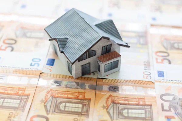 Buying and building a house.House and money. Real estate market. house with gray roof on euro banknotes background. . High quality photo