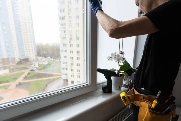 Master in gloves adjusting pvc windows with screwdriver closeup. Installation of plastic windows repair and maintenance concept. High quality photo