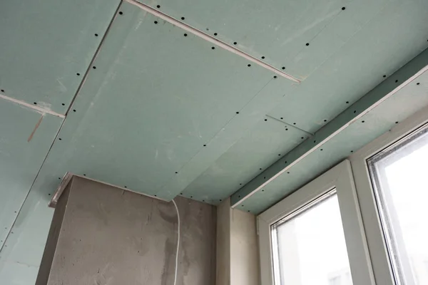 stock image Installation of drywall. Workers are using screws and a screwdriver to attach plasterboard to the ceiling. High quality photo