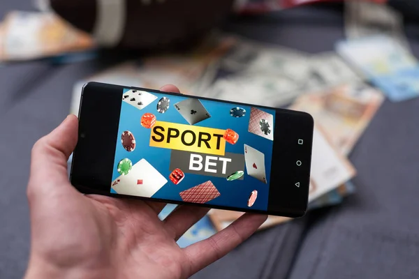 オンラインスポーツへの賭け スマートフォンとサッカーボールを持った手の背景にドルが落ちています 創造的な背景 ギャンブル — ストック写真