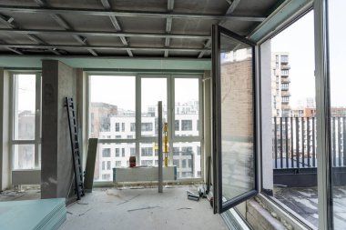 İnşaat işçisi asılmış tavanı alçıpanla birleştiriyor ve alçıpanı tornavidayla tavandaki metal çerçeveye yerleştiriyor. Tadilat, inşaat ve kendin yap. Yüksek kalite fotoğraf