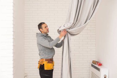 İşçi duvara pencere perdesi çubuğu yerleştiriyor