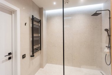 Banyo gri ve beyaz zemin ile modern bir tarzda. Aydınlık lambaları, Masa üstü ahşap çekmece ve lavabo, banyo duş ve cam bölme, havlu askısı ile bir askı ile büyük bir ayna.