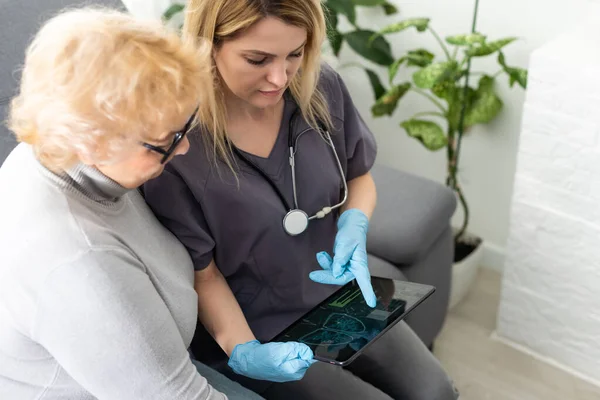 一位年轻的医生拿着一台平板电脑和她的病人交谈的镜头 — 图库照片
