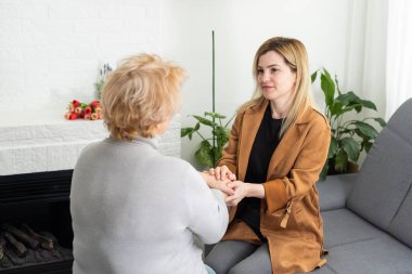 Destekçilerin yakın çekimi. Genç bir kadının, yaşlı bir kadının elini rahatça tutarken yakın plan fotoğrafı. Yaşlı bir kadının elini tutan kadın bakıcı..