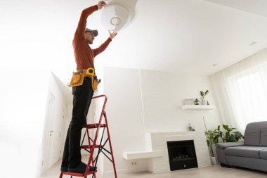 Elektrikçi adam dış ışık üzerinde çalışıyor, eve LED yedek lamba takın. Bakım kavramı