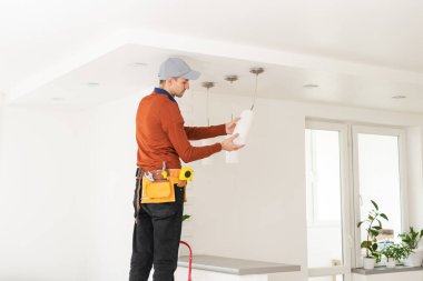 Üniformalı elektrikçi içeride tavan lambasını tamir ediyor..