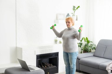 Evde antrenman. Sportif son sınıf öğrencisi laptopta ders izlerken yoga tahtası yapıyor oturma odasında egzersiz yapıyor, boş yer, panorama..