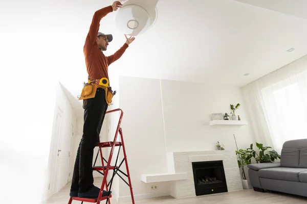 Electrician man working on exterior light, install LED replacement lamp at home. Maintenance concept