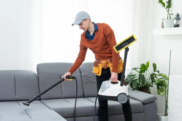 Dry cleaning worker removing dirt from sofa indoors.