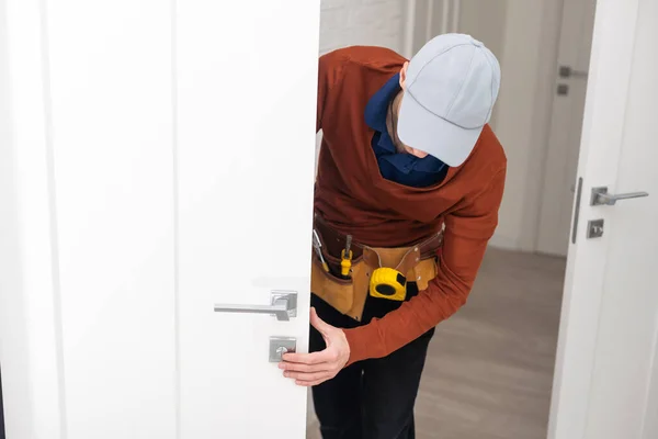 stock image Young handyman installing a white door.