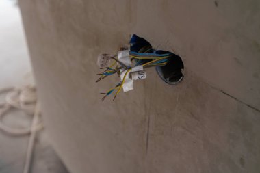 Yeni elektrik tesisatı, plastik soket ve elektrik kabloları alçılı bir duvara takılacak. DIY ev yenileme konsepti. Yüksek kalite fotoğraf