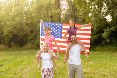 Gün batımında Amerika bayrağıyla mutlu bir aile..