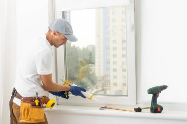 Eldivenlerde uzman. PVC pencerelerini tornavidayla kapatıyor. Plastik pencere onarım ve bakım konsepti kurulumu