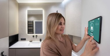 Akıllı ev sistemini kullanan ya da evden çıkmadan önce modern alarm sistemini çalıştıran hoş bir kadın. Mutlu kadın eve ya da daireye döndüğünde kolay güvenlik teknolojisini kapatıyor..