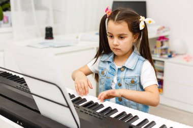 Piyano çalan kız için ev müziği dersi. Karantina sırasında çocuk için evde aktivite fikri. Müzik konsepti.