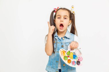 An artist on an isolated background, a little girl with paints in her hands, childrens creativity