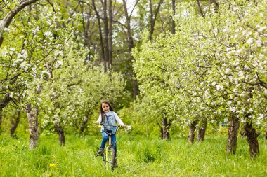 Ağacın yanında çiçekli bisikletli küçük kız..