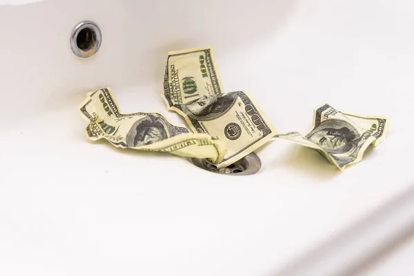 Money is thrown away in the sink. This photo concept illustrates the financial condition of a business that is failing or going bankrupt so that it only wastes money without results.
