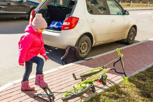 stock image a little girl pumps up a bicycle tire.