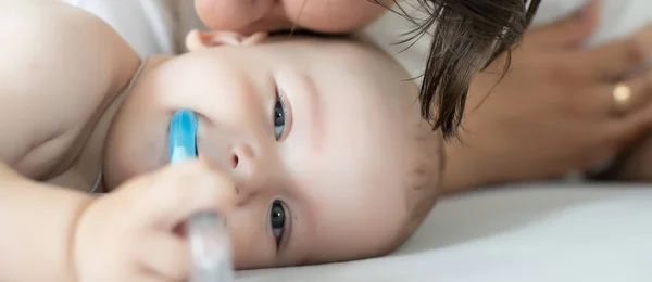 stock image Mother and child on a white bed. Mom and baby boy in diaper playing in bedroom. Parent and little kid relaxing at home. Family having fun together