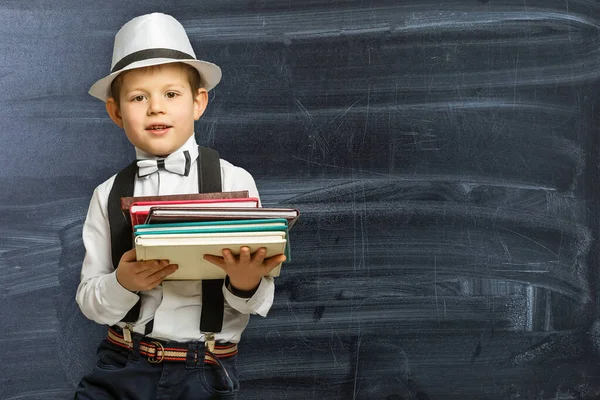 学校に戻る 面白い小さな男の子の眼鏡を黒板に指している 本とバッグを持つ小学校の子供 本のある子供 — ストック写真