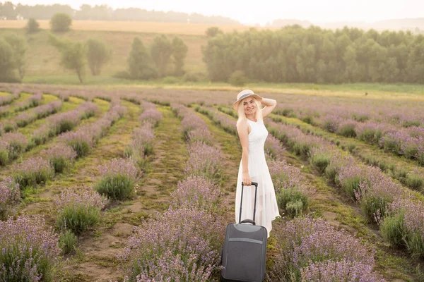 woman with luggage in lavender field.