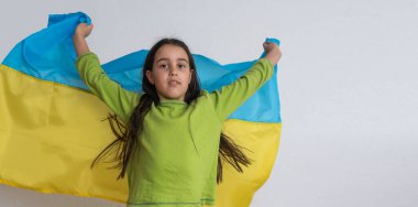 Çocuk Ukrayna 'nın mavi ve sarı bayrağını bembeyaz üzerinde taşıyor. Ukrayna 'nın Bağımsızlık Günü. Bayrak Günü. Anayasa günü. Geleneksel Ukrayna bayrağıyla nakışçı kız.