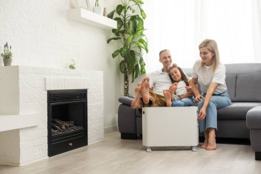 Family warming near electric heater at home