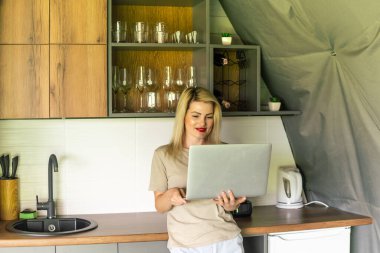 Evde dizüstü bilgisayarı ve masada bir fincan kahveyle neşeli bir kadının portresi. 30 yaşında bir kız, arkadaşları ve ailesiyle çevrimiçi olarak görüşüyor. Telework konsepti