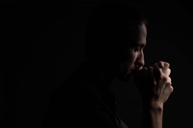 Dua sadık olgun adam yakın çekim, katlanmış içinde ibadet Tanrı'yla baş aşağı ve gözleri dini şevk içinde kapalı eller. Siyah arka plan. Din, inanç, dua ve maneviyat için kavram.