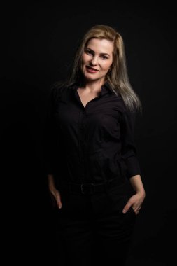 Gri arka planda siyah bluzlu, orta yaşlı güzel bir kadın.