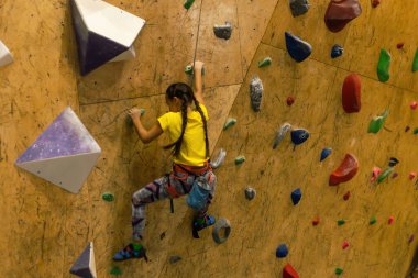 Boulding, duvara tırmanan küçük bir kız ve çok renkli kabzalara tırmanan bir dağcı. Boş zaman aktivitesi.