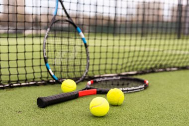 tennis racket with balls on green background clipart