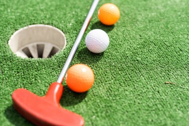 Mini golf ball on green headed towards hole. clipart