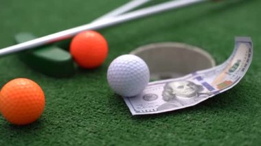 Mini golf sopası, top ve para yapay çimlerin üzerinde..