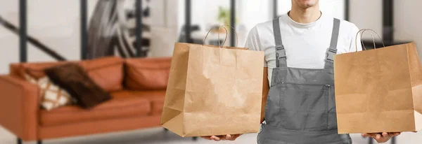一个微笑的送货员手里拿着纸袋和食品容器 食肆的优质服务 — 图库照片