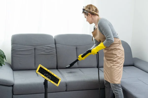 Dry cleaners employee removing dirt from furniture in flat, closeup