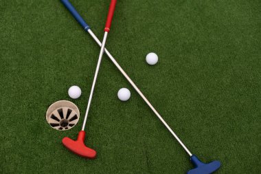 Sentetik çimlerin üzerinde golf topları olan renkli golf sopaları..